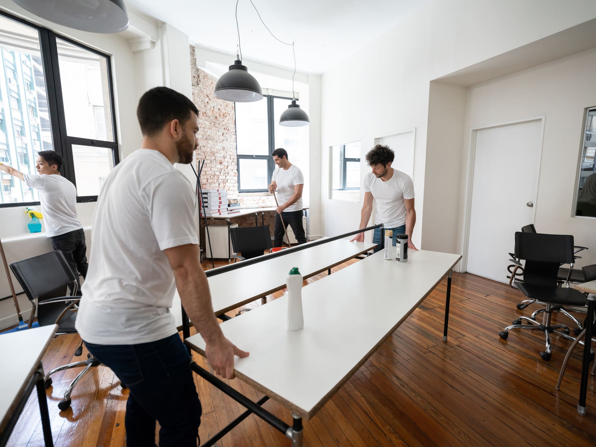 Team of male cleaning contractors moving a desk