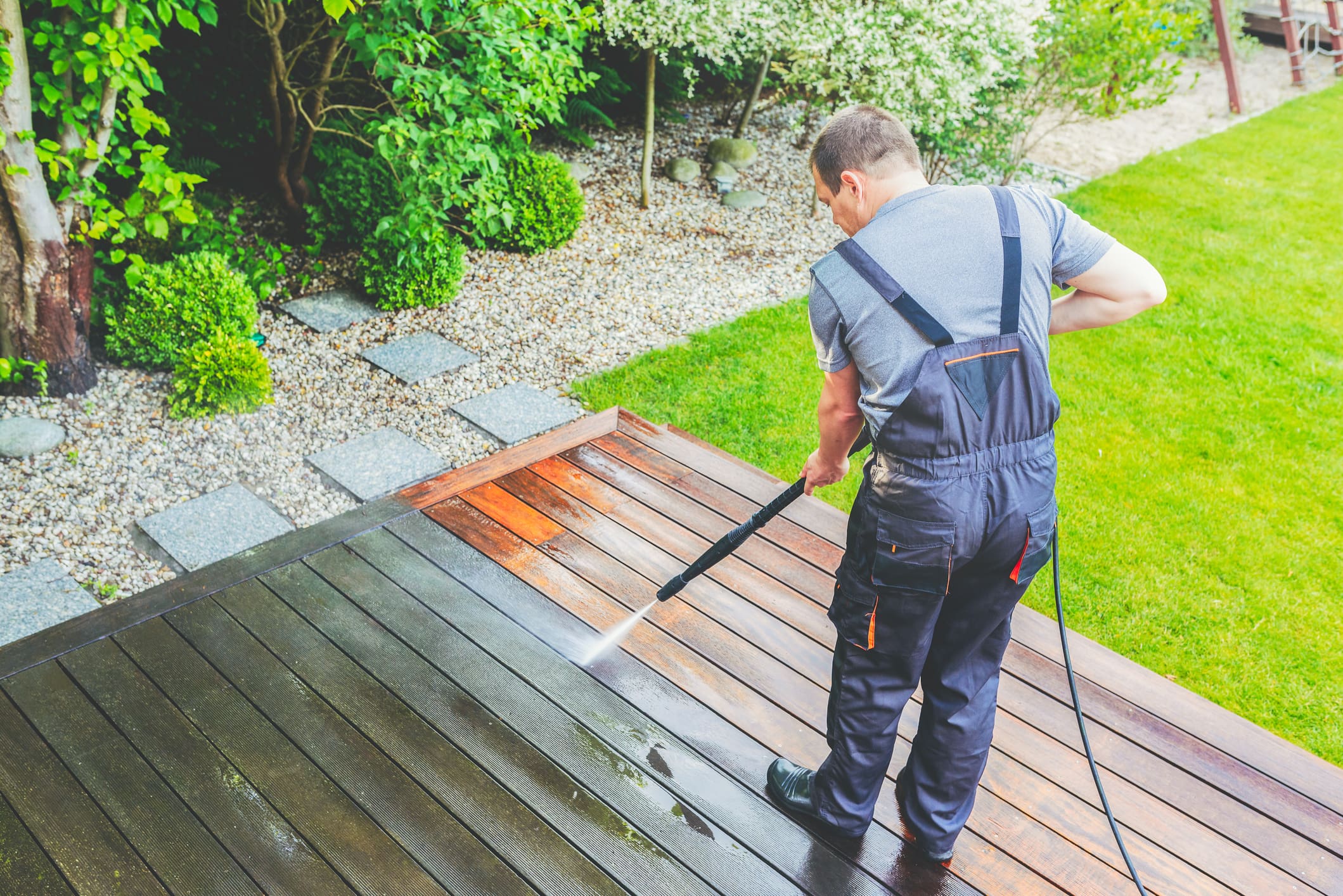 Cleaning terrace with a power washer - high water pressure cleaner on wooden terrace surface