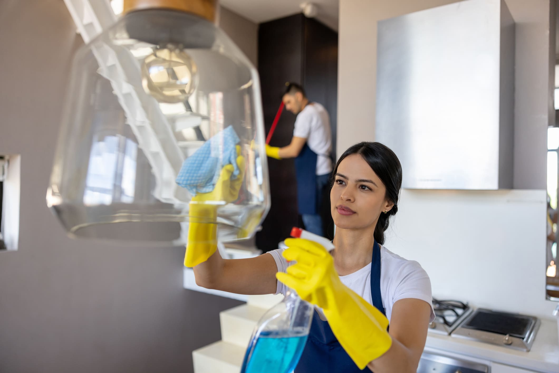 Professional cleaner cleaning a lamp in the kitchen of a house