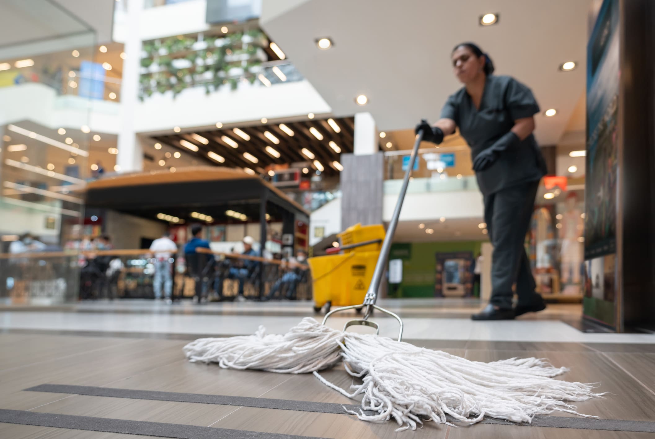 Cleaning lady mopping the floor at a shopping centre